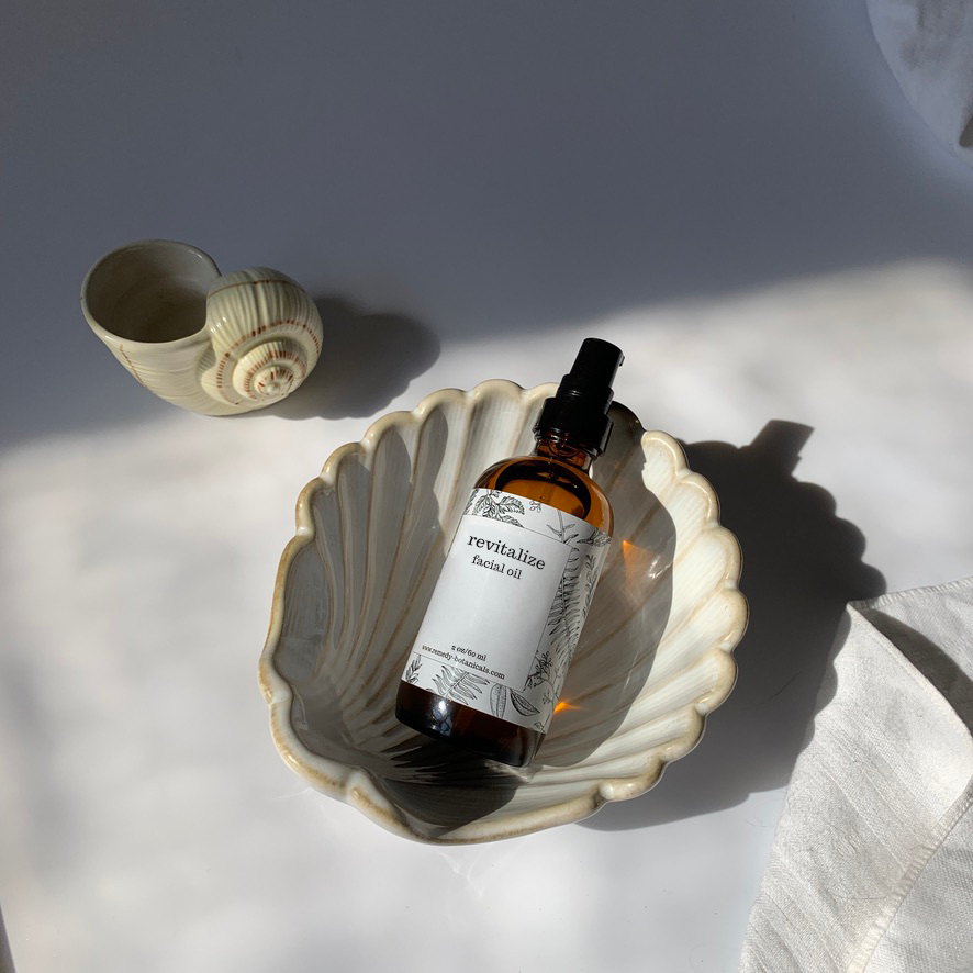 Top view of a bottle of Revitalize facial oil in a decorative pearl shell figurine.