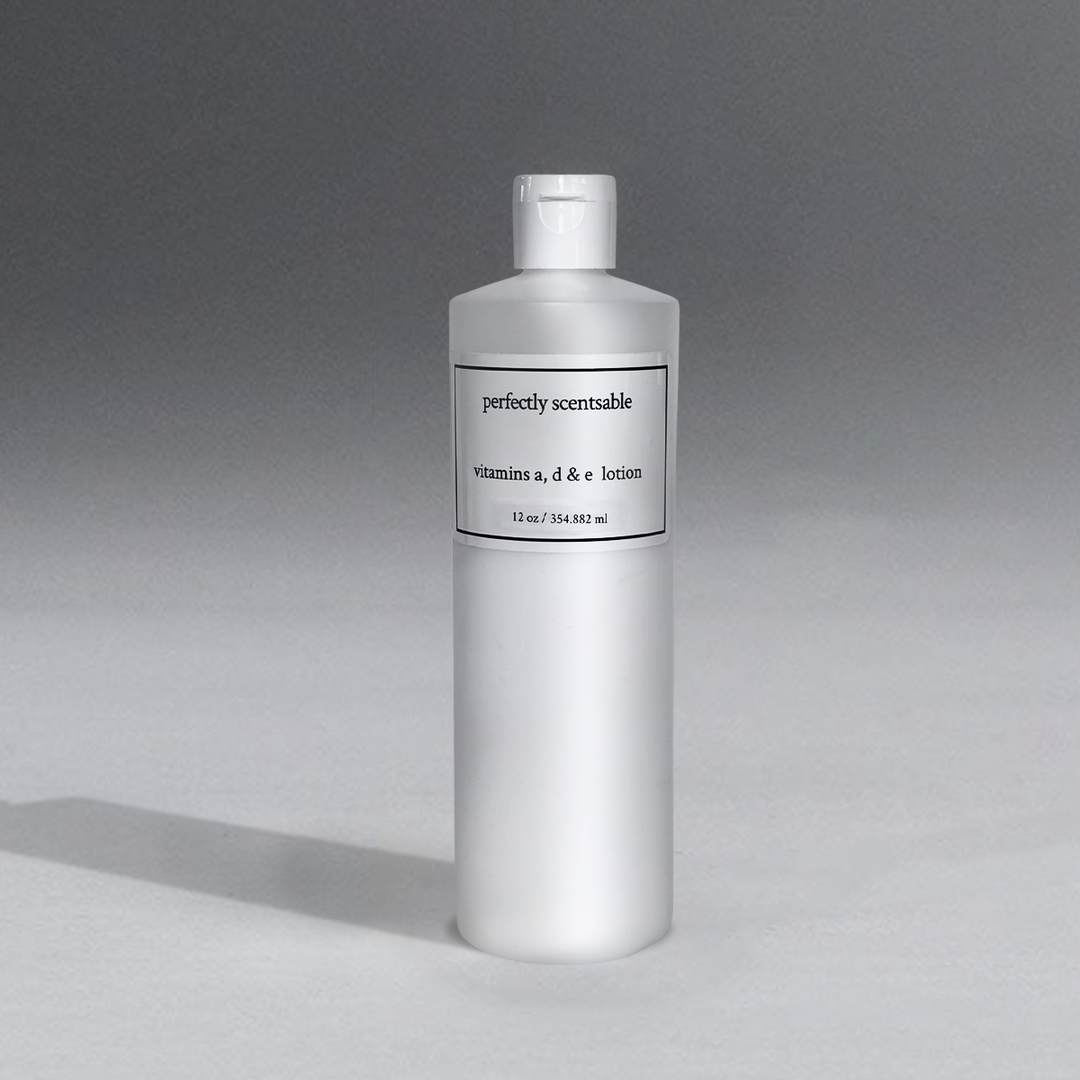 White bottle of Perfectly Scentsable Vitamins A, D & E Lotion, 12 oz size, with a simple black and white label, placed against a soft gradient gray background with subtle shadow cast on the surface.