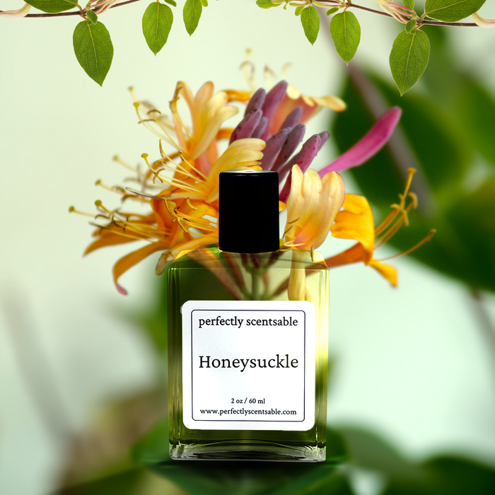 Perfectly Scentsable Honeysuckle perfume oil, 2 oz/60 ml square glass bottle with black cap in front of blooming honeysuckle flowers and green leaves.