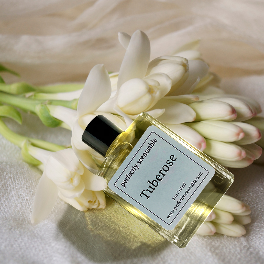 Perfectly Scentsable Tuberose perfume oil bottle resting on white fabric over fresh white tuberose blooms.