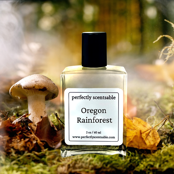 Perfectly Scentsable Oregon Rainforest perfume oil, 2 oz/60 ml square bottle on a mossy forest floor beside a mushroom and fallen leaves, misty backdrop.