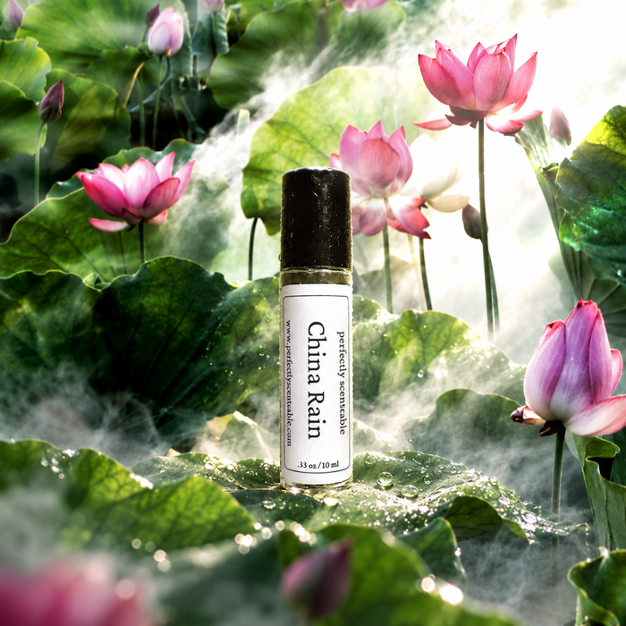 China Rain roll-on perfume bottle displayed among lush green lotus leaves and pink lotus flowers, surrounded by soft mist and sparkling water droplets in bright natural light.