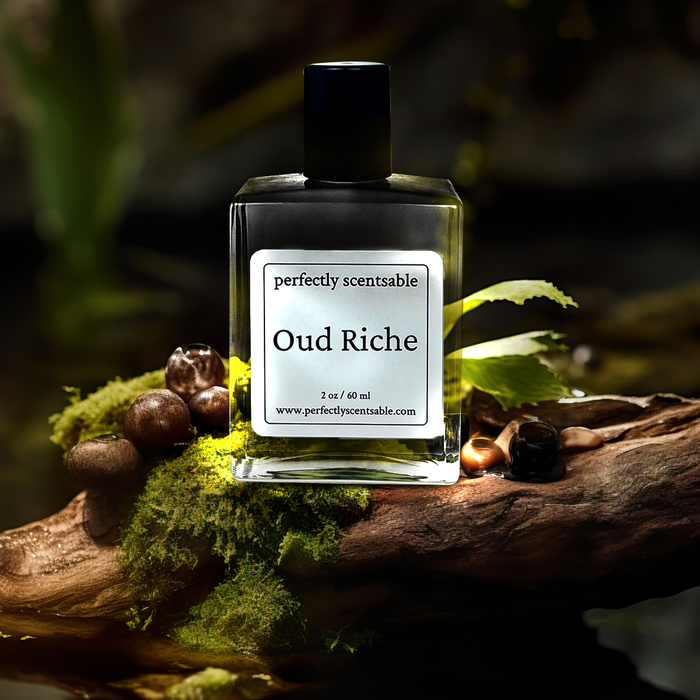 Perfectly Scentsable Oud Riche perfume oil, 1 oz/30 ml bottle on moss-covered driftwood with small brown seeds, forest stream backdrop.