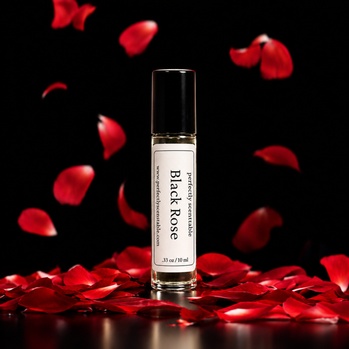 Black Rose roll-on perfume bottle centered against a black background, surrounded by vivid red rose petals falling through the air and scattered across a reflective surface.