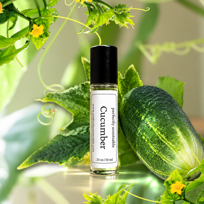 Cucumber roll-on perfume bottle displayed beside a fresh green cucumber covered in water droplets, surrounded by cucumber leaves, curling vines, and small yellow blossoms in bright natural light.