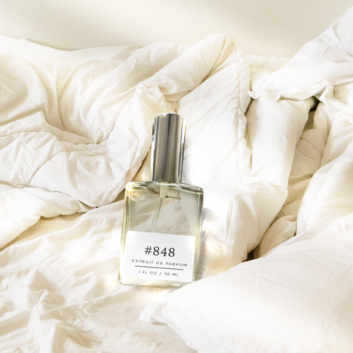Perfectly Scentsable #848 Extrait de Parfum bottle resting on sunlit, rumpled white bedding.