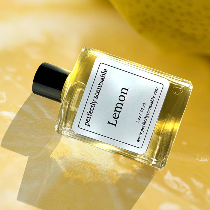 Lemon perfume oil bottle, tilted on a glossy yellow surface with a lemon in soft focus behind.