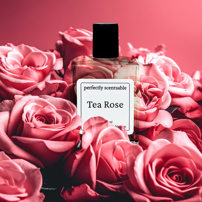 Perfectly Scentsable Tea Rose perfume oil bottle nestled among blooming pink roses on a soft rose-pink background