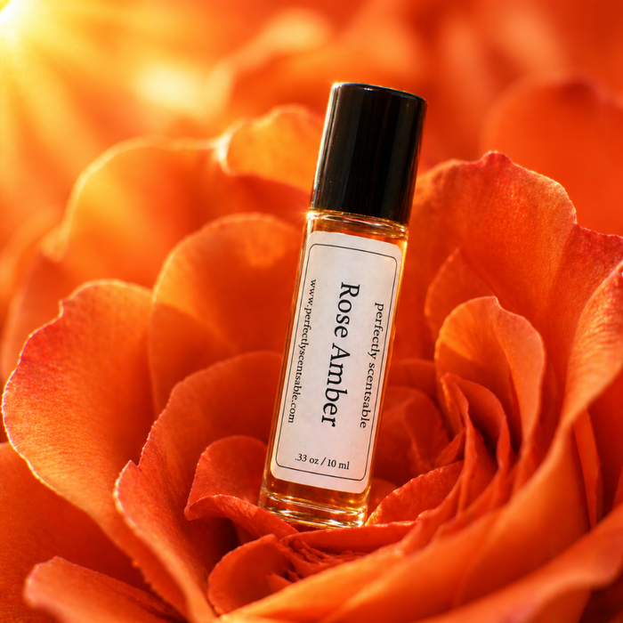 Rose Amber roll-on perfume bottle nestled among rich orange-red rose petals, illuminated by warm golden light with a soft glowing background.