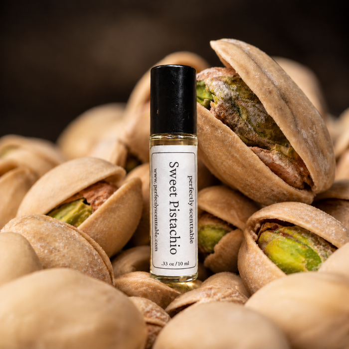Sweet Pistachio roll-on perfume bottle standing among open pistachio shells, with green pistachio nuts visible and warm brown lighting creating a rich, nutty atmosphere.