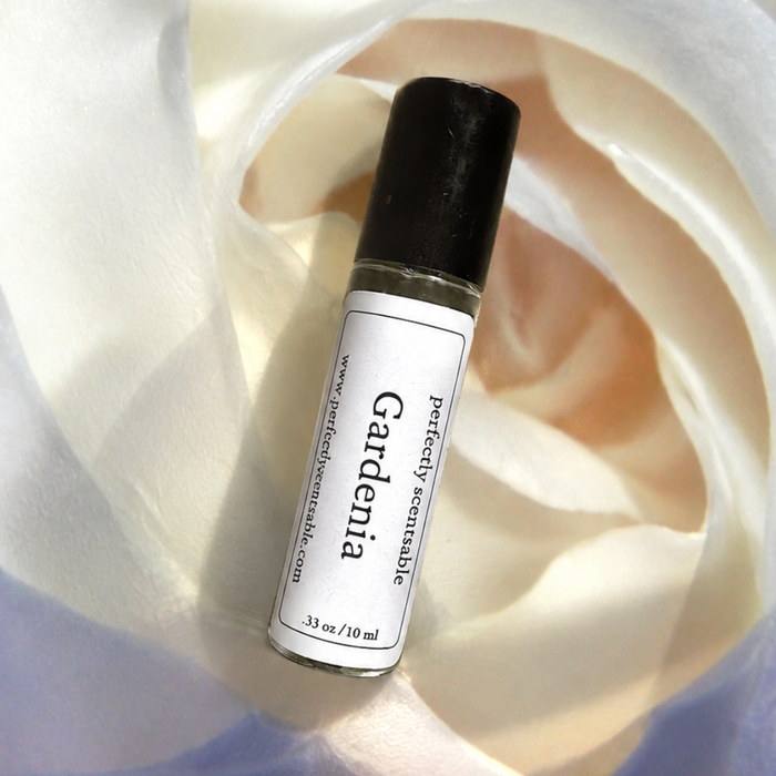 Gardenia roll-on perfume bottle resting among soft white gardenia petals, illuminated by gentle natural light with creamy ivory tones and subtle shadows.