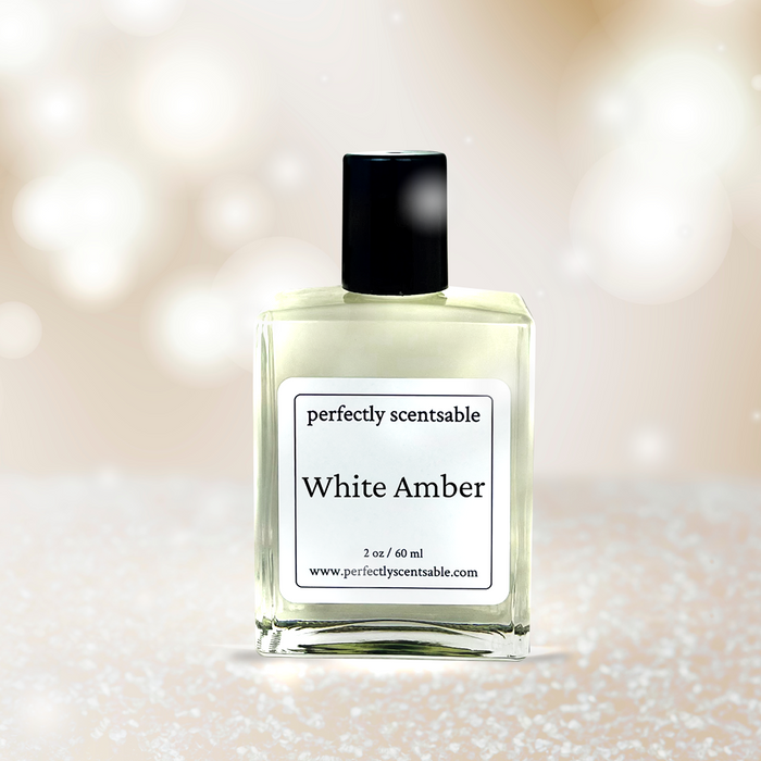 Perfectly Scentsable White Amber perfume oil — 2 oz (60 ml) clear glass bottle on a soft ivory bokeh background with subtle sparkle