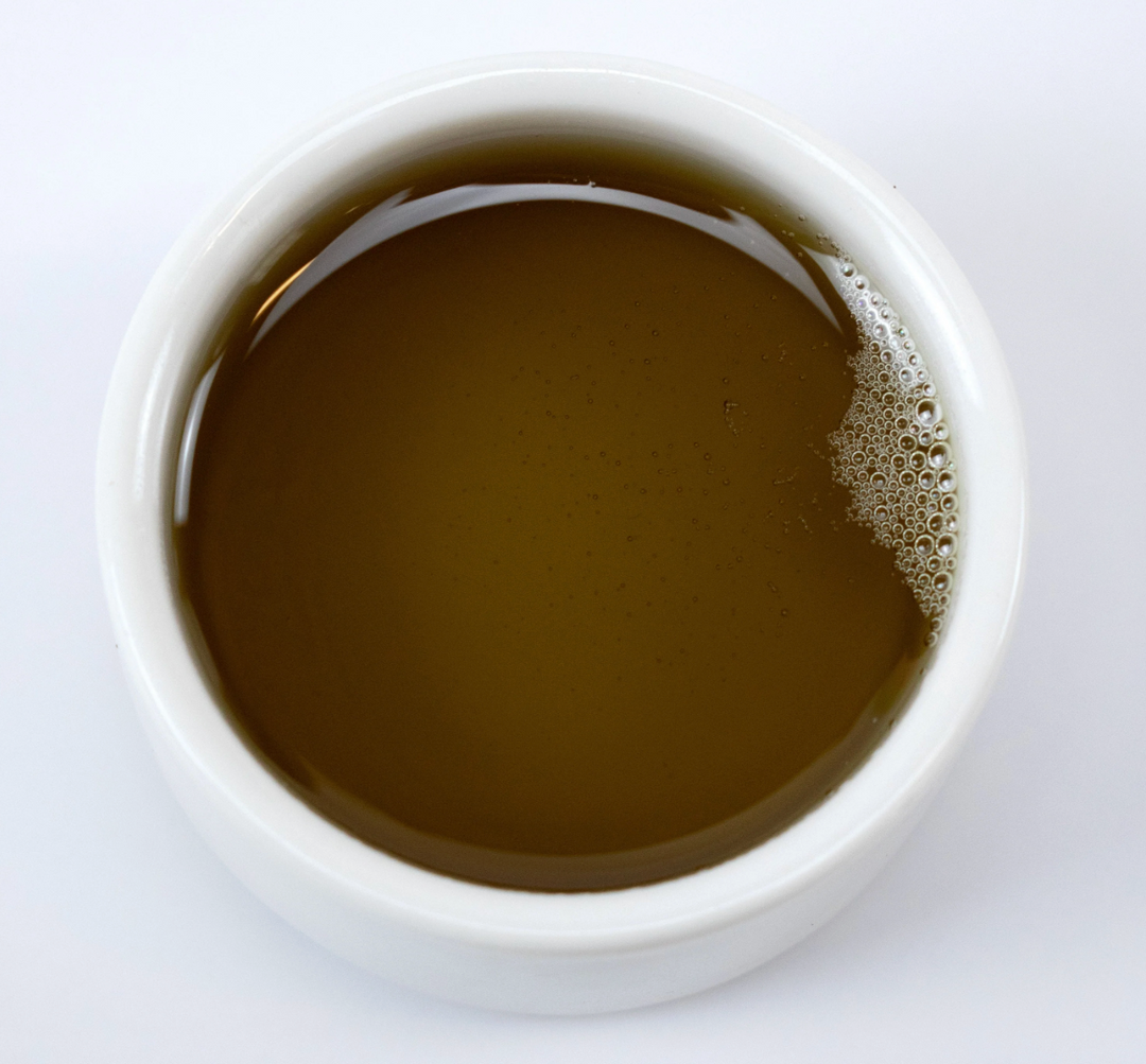 White cup filled with dark liquid on a white background