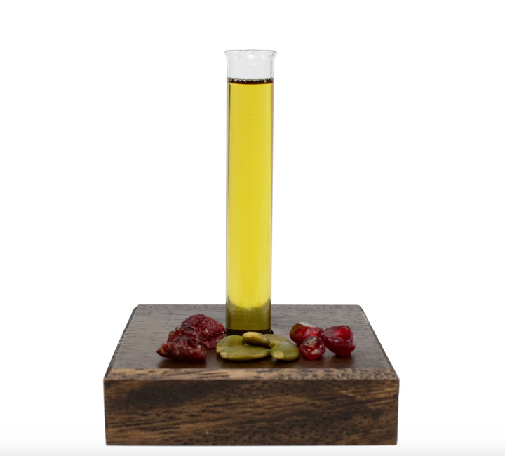 Glass tube with yellow liquid on a wooden block with fruits against a white background