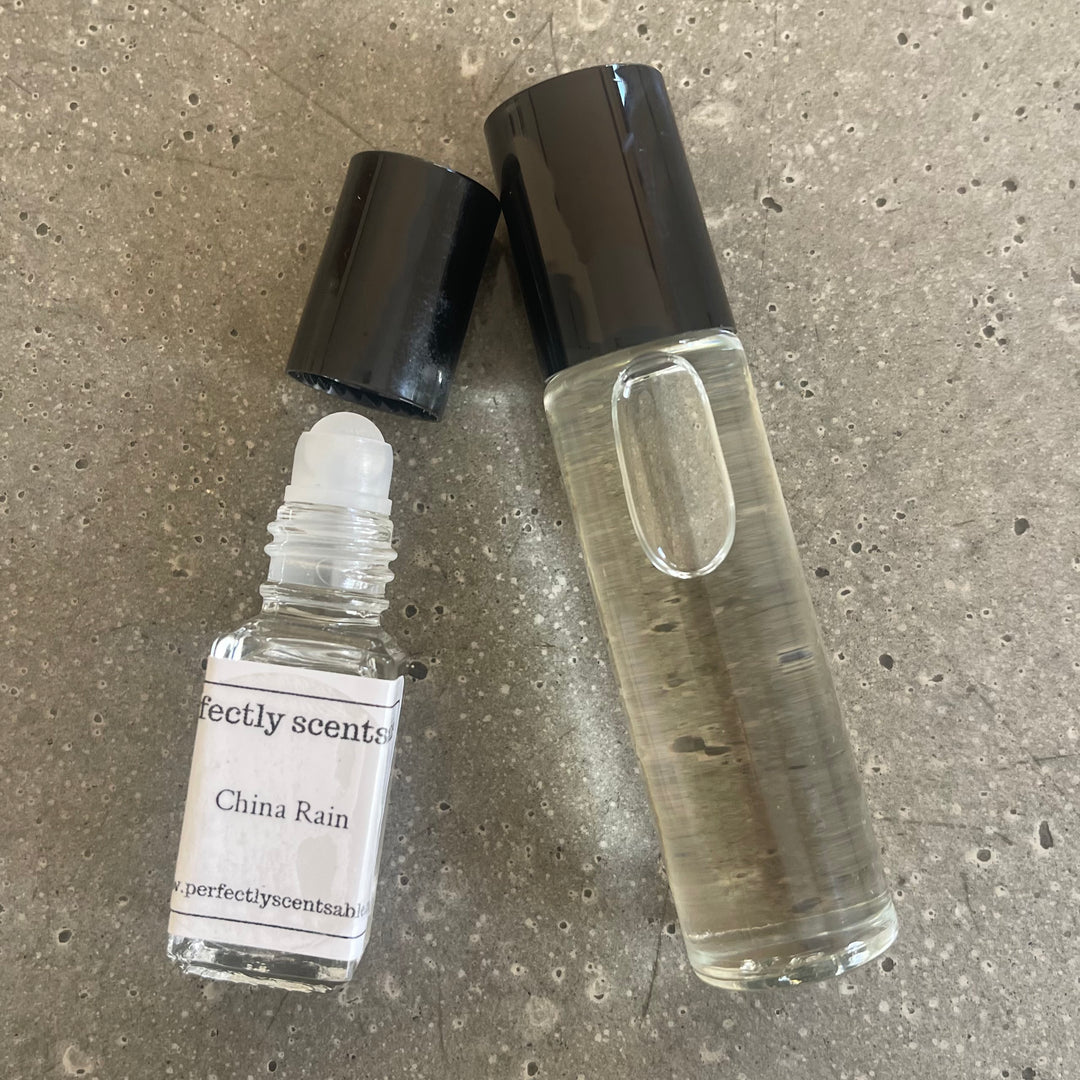 A single mini roller bottle lying down beside a rollerball perfume oil positioned on the right, creating a simple and elegant arrangement.