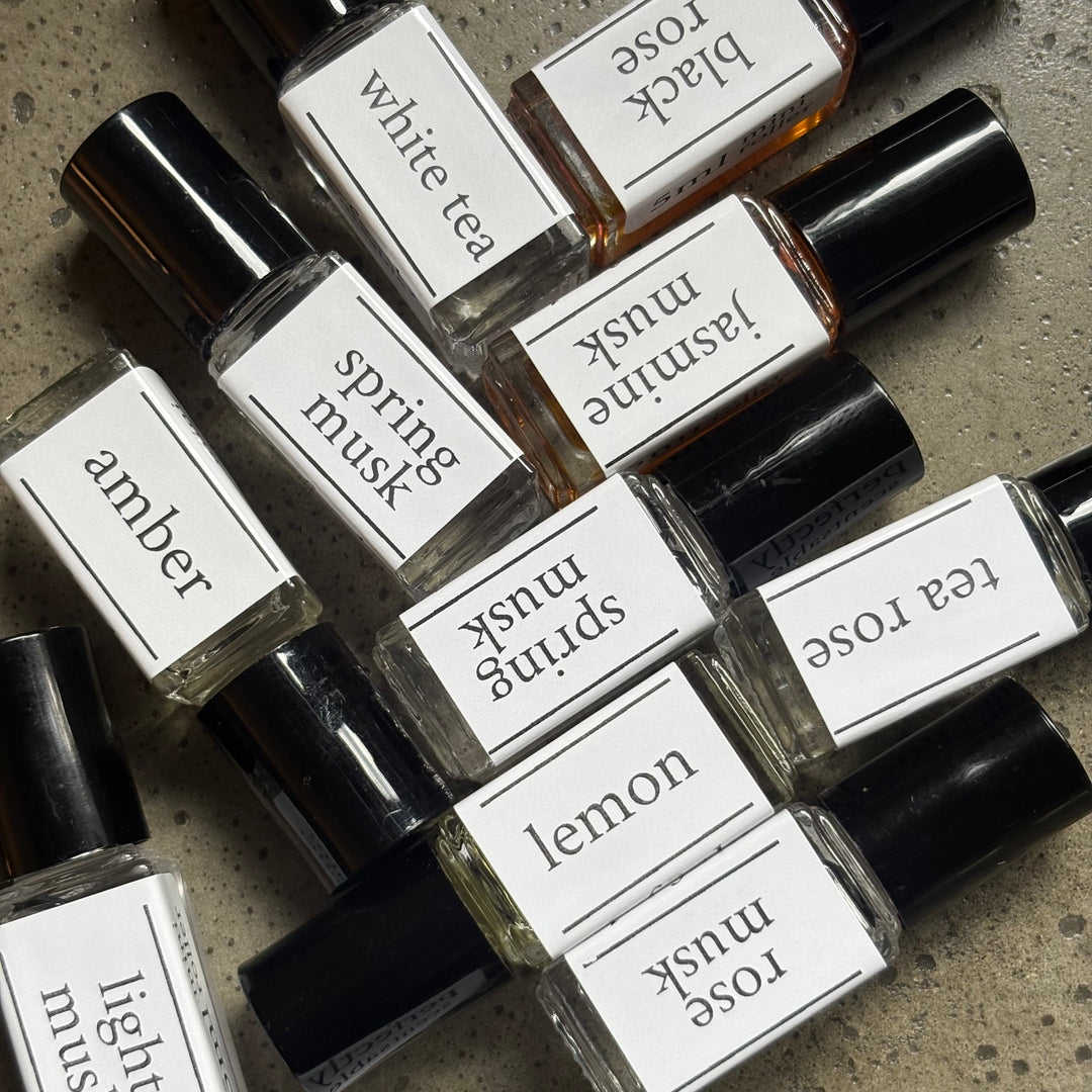 Collection of small perfume bottles with labeled names on a textured surface