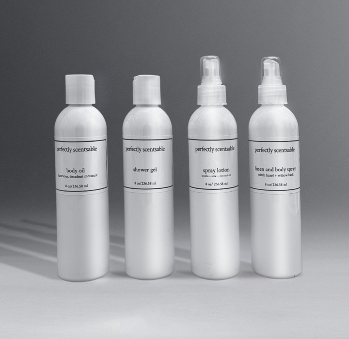 Perfectly Scentsable body care collection featuring four 8 oz white bottles: body oil, shower gel, spray lotion, and linen & body spray, set against a gray background.