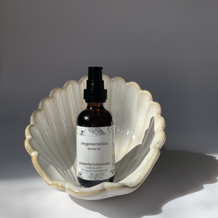 An regeneration facial oil, standing on a pearl figurine on a gray blackground.